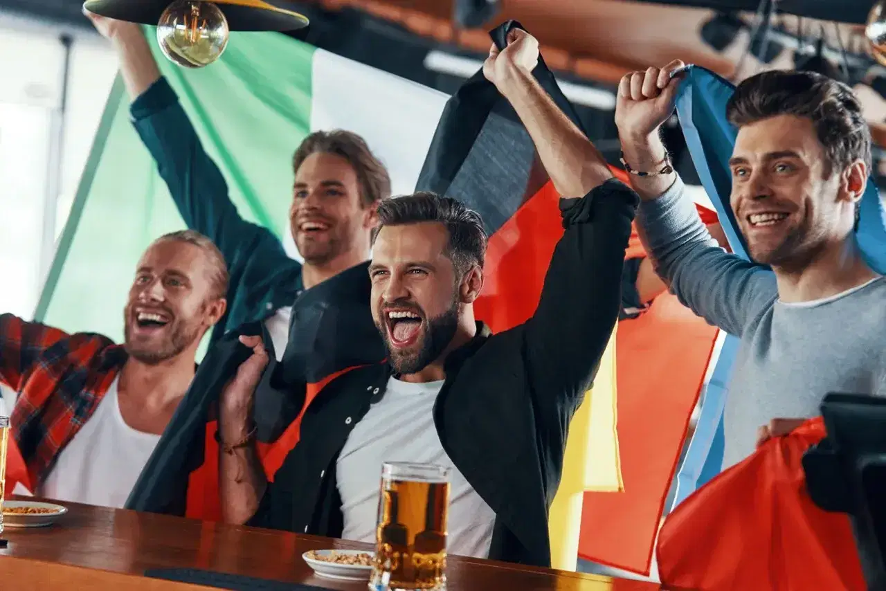 Men cheering at bar with beer and flags